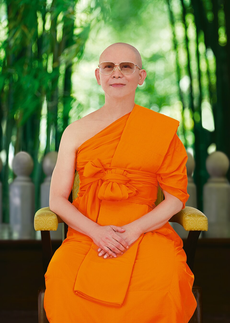 Luang Por Dhammajayo seated in saffron robes among bamboo